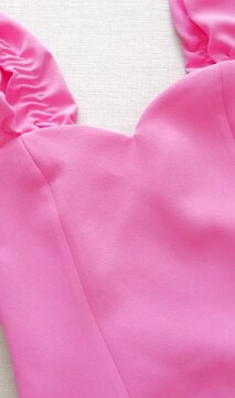 Close-up detail of pink satin dress fabric with straps and bodice