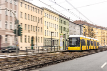 Obraz premium Yellow tram rushing through city blocks. Urban tram.