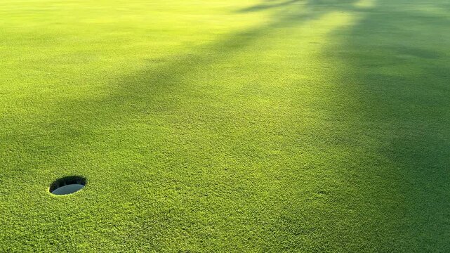 Twilight sun hits hole cut out in golf putting green