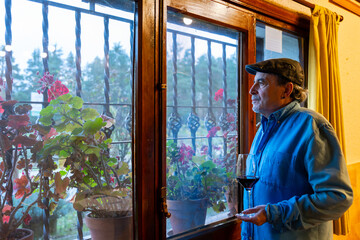 Mature man enjoying red wine looking through window