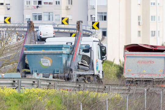Waste removal truck transporting skip container on highway