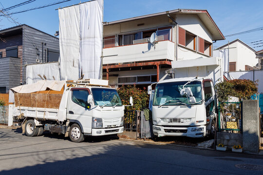 住宅街の解体工事現場と廃材を運搬するトラック