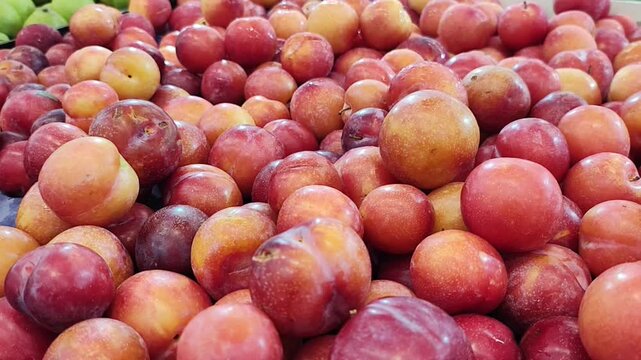 Ameixas vermelhas e amarelas frescas em uma cesta no mercado