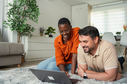 Happy couple smiling and using laptop at home