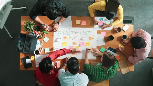Top down aerial view of business team making scrum task board at meeting room. Group of people writing at paper and sticky notes for making kanban board to manage work flow. Time lapse. Convocation.