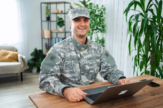 Smiling soldier using laptop at home