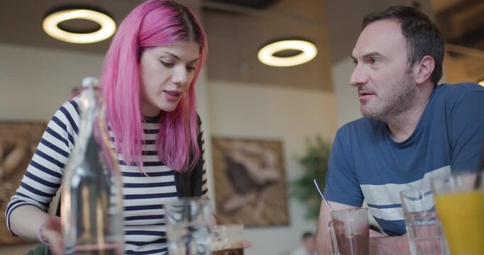 Dynamic conversation between model and friend in cozy cafe setting during afternoon gathering