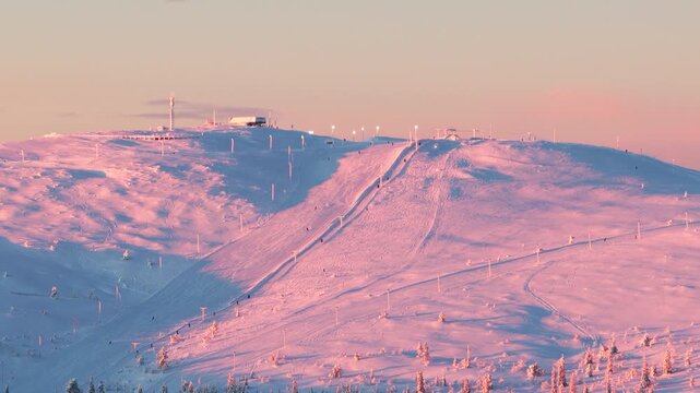 Aerial Telephoto View of Skiers on Snow Covered Mountain Slope at Winter Sunset