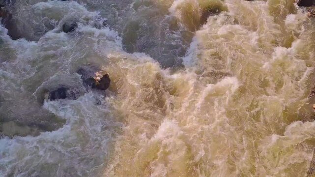 Aerial view of churning, muddy brown floodwater.