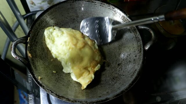 Cooking and whisking an omelet mixture in a frying pan on a stove. The image shows food preparation, kitchen activity, and the process of making a traditional homemade omelet.
