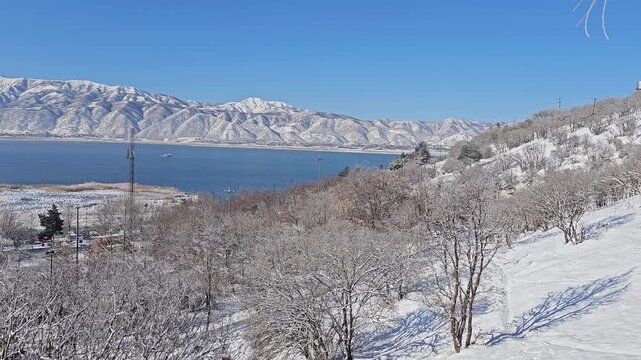 Winter lake surrounded by snowy trees and Zagros mountains under a clear blue sky, creating a peaceful and scenic natural landscape.  
📍Zaribar lake, Marivan