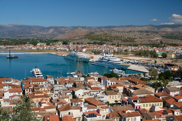 Obraz premium a view of the rooftops of Nafplio from above, with mountains and yachts in the background