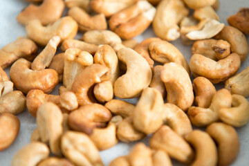 Fototapeta premium Cashew nuts background. A bunch of cashew in a plate, organic, bio, imperfect, irregular sizes and broken