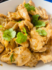 Close-up of Authentic Thai Garlic Pepper Chicken (Gai Pad Kratiem Prik Thai) Garnished with Fresh Cilantro in a White Bowl © Heavenlyflower