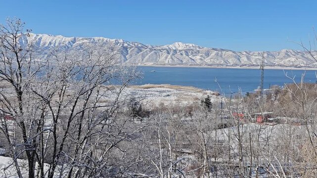 Winter lake surrounded by snowy trees and Zagros mountains under a clear blue sky, creating a peaceful and scenic natural landscape.  
📍Zaribar lake, Marivan
