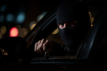 Masked criminal holding knife inside car at night