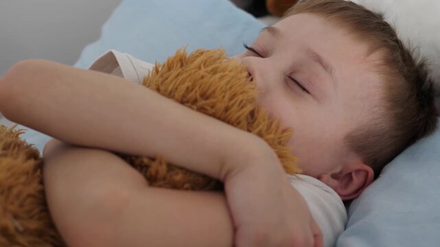 A small child is sleeping peacefully, hugging a soft plush toy. Close-up of a child's face with closed eyes, an atmosphere of comfort, safety and tranquility. The concept of childhood