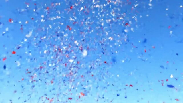 Confetti scattered against a clear blue sky with a shallow depth of field, conveying a festive and celebratory mood.
