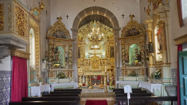 Catholic church interior with gilded main altar side altars pews and chandeliers