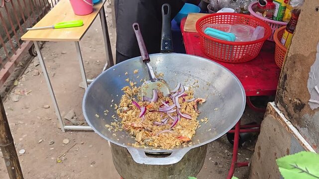 Chef preparing cooking Thai traditional delicious food Stirring fried rice with seafood and in frying pan outdoor at street cafe. Khao pad talay - traditional thai cousine from jasmine rice