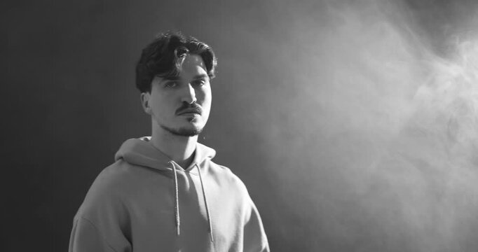 Man in hood on dark background with smoke. Black and white effect