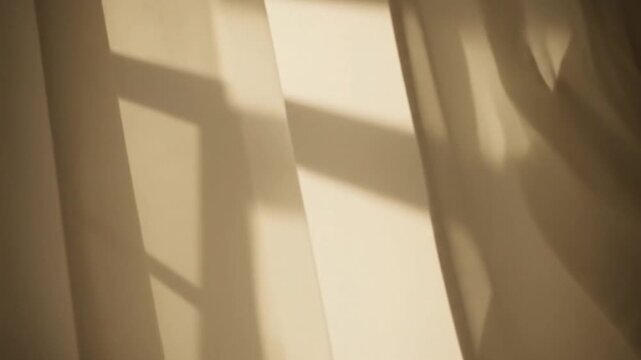 Warm sunlight filtering through sheer curtains, casting geometric shadows from a window frame indoors.