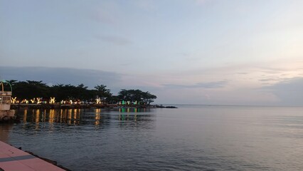 Fototapeta premium Peaceful sunset reflecting over calm water with sky and clouds near the horizon