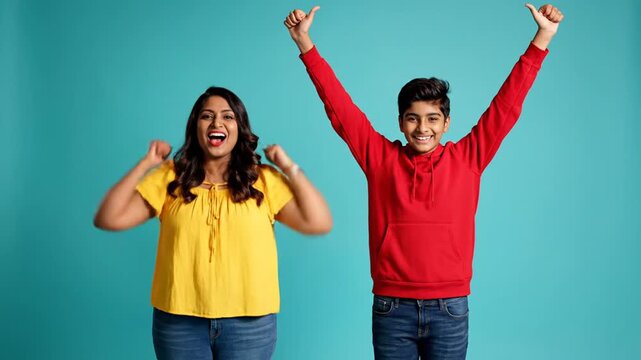 Cheerful Indian mother and son standing on blue studio background