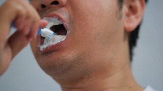  The man brushes his teeth with toothbrush with toothpaste close-up.