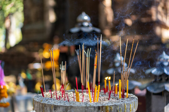 Incense and fire candles with ashes and smoke in Incense burner from Buddhists for make a wish or pray to buddha statue or sacred deities by belief in Buddhism for lucky in Asia at Thailand temple