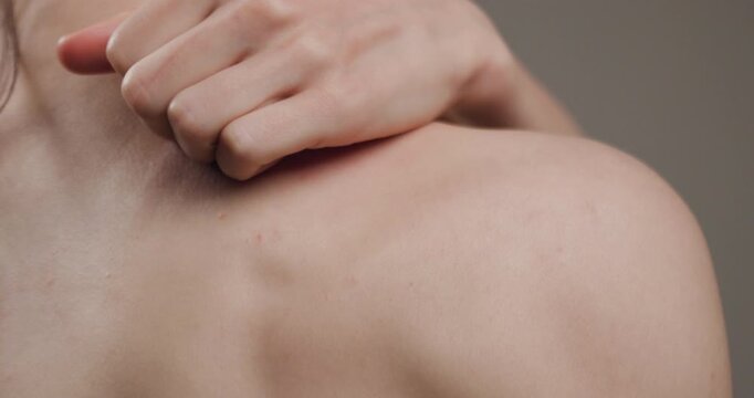 Close-up of a person pinching their shoulder, showing skin texture and details