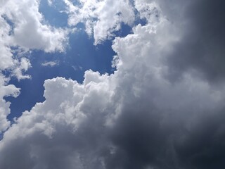 Obraz premium Dramatic Cloudscape with Blue Sky and Dark Storm Clouds, Weather Contrast Background, Moody Atmospheric Nature Scene