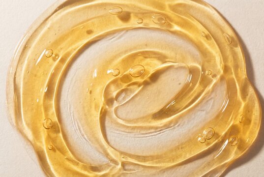 Translucent yellow orange cosmetic gel texture with bubbles spread on light background