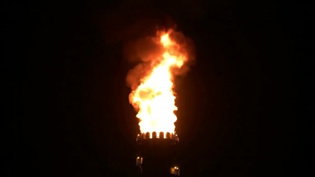 Large fire burning at night with flames and smoke.