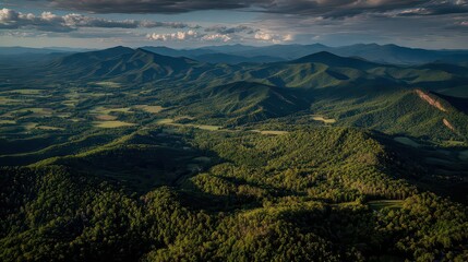 Scenic Green Forest Hills with Dramatic Cloudy Sky Golden Hour Sunlight Creates Contrasting Shadows in Landscape Aerial View of Trees and Hills