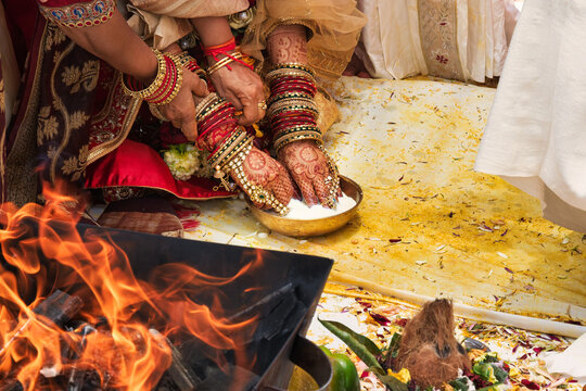 Indian Bride and Groom Offering to Sacred Fire Agni During Hindu Wedding hands are joined over a bowl of milk