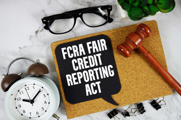 FCRA Fair Credit Reporting Act text on speech bubble with alarm clock and wooden gavel on marble background