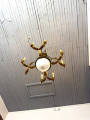 Vintage ornate chandelier hanging from gray wooden slatted ceiling