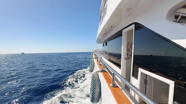 Wide side view of luxury double decker yacht with tinted windows floating fast in the Sea