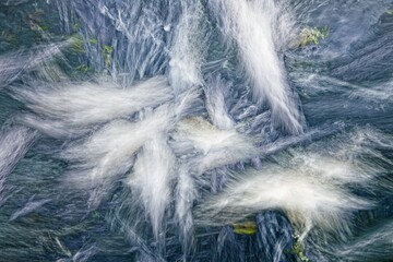 Fototapeta premium Whispers of the Stream: The mesmerizing blur of a stream's dance, as water cascades over rocks, evoking a sense of tranquil movement, serenity and timelessness.