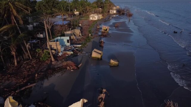 dolly shot, coast and small houses affected by the elevation of the ocean level for climate change