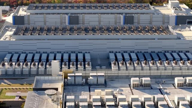 Expansive aerial view of a large scale data center with cooling units , chillars on the roof and power generators.