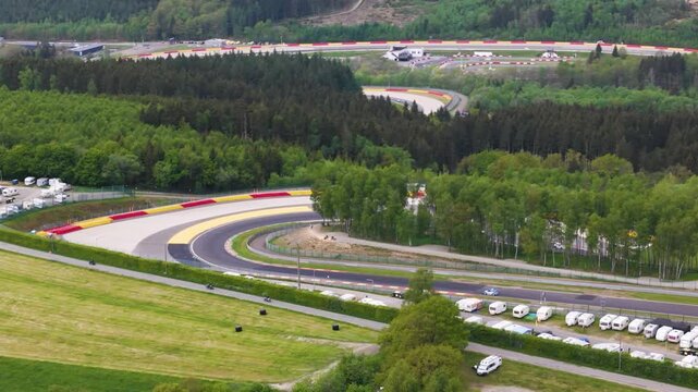 centers light blue car threading tight curve beside clustered caravans slopes frame circuit spa francorchamps ardennes belgium wide angle spa-francorchamps motorsport caravan cluster 