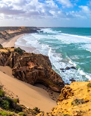 Aerial view of a rugged coastline featuring a sandy beach, crashing waves, cliffs, and a bright blue sky