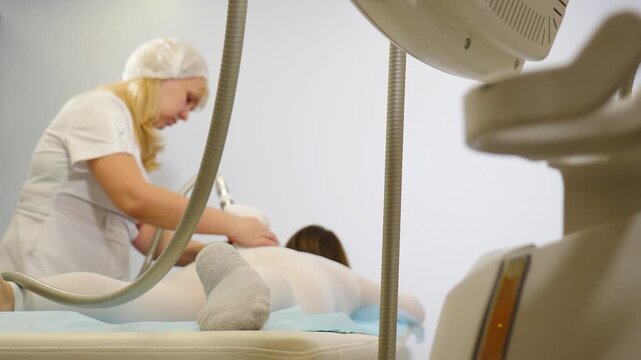 LPG massage, Professional body contouring treatment for cellulite reduction and lymphatic drainage at a modern beauty clinic spa. cosmetologist hands manipulating hardware gadget. Slimming thighs. 4 k