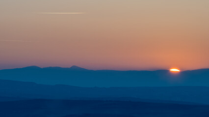 Obraz premium Sunset over layered mountain silhouettes minimal landscape