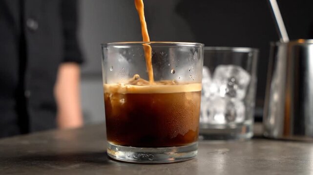Close-up shot of espresso being poured into a glass with ice, creating a refreshing coffee drink