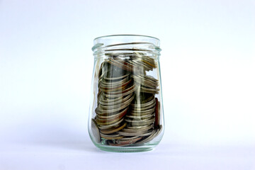 A coin in a glass jar, against a white background, financial concepts, investment, saving.