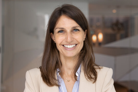 Positive businesswoman close up head shot, office portrait. Professional woman dressed in elegant business attire looking at camera with joyful expression, exude leadership, confidence and competence