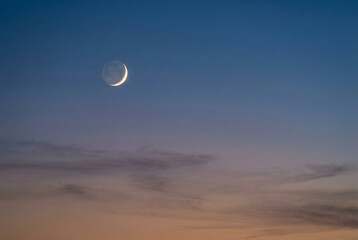 Obraz premium Crescent moon at blue hour with purple and orange gradient sky